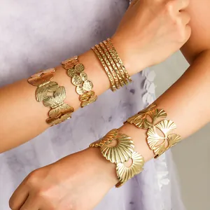 Detailweergave van luxe gouden vlinder- en bladmanchetten op de arm van het model