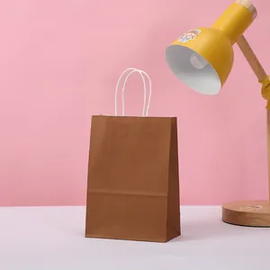 Detailed view of a minimalist brown kraft paper gift bag featuring sturdy white twisted paper handles