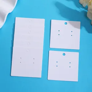 Close-up of white blank earring display cards on a blue background