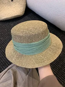 Detailed macro shot showing the fine weave texture of a flat-top straw hat with green band
