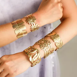 Detailweergave van meerdere vintage gouden roestvrijstalen manchetarmbanden op een model