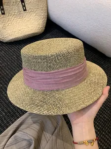 Detail of a French flat-top straw hat featuring a stylish pink fabric ribbon for summer