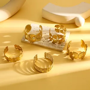 Detailweergave van vijf gouden retro roestvrijstalen armbanden met natuurlijke patronen.