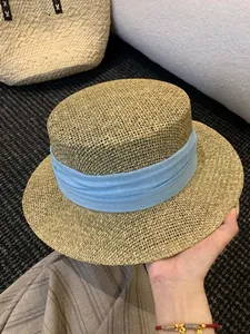 Close-up of the fine woven texture and the light blue fabric band on the French straw hat.