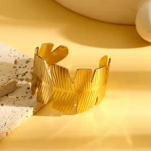 Detail van een gouden roestvrijstalen manchetarmband met geometrisch bladmotief