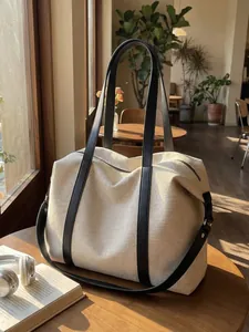 Large capacity cream canvas tote bag with black leather straps on a wooden table