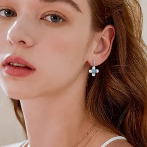 Modelo elegante luciendo pendientes de flores azul degradado con detalles de diamantes