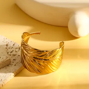 Gedetailleerd aanzicht van een vintage gouden veerarmring van gepolijst roestvrij staal.
