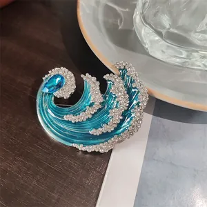 Vista dettagliata della spilla blu a forma di onda con strass luccicanti e cristallo