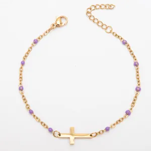 Gros plan détaillé du bracelet croix en acier inoxydable plaqué or 18 carats avec perles mauves