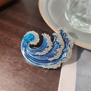 Vista dettagliata di un'elegante spilla a forma di onda con cristallo blu e strass