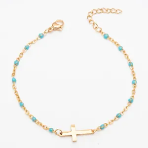 Bracelet croix en acier titane plaqué or avec perles en émail turquoise pour femme.