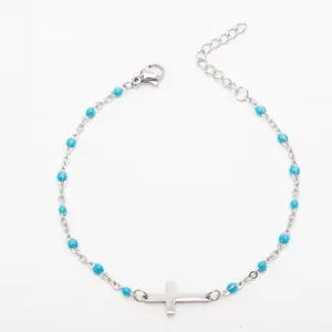 Gros plan d'un bracelet croix en acier inoxydable avec des perles en émail turquoise