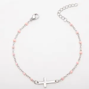 Vue détaillée d'un bracelet en acier inoxydable argenté avec perles roses et une croix
