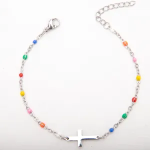 Détail d'un bracelet croix en acier inoxydable argenté avec perles colorées.