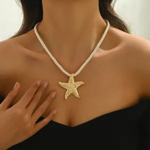 Dettaglio collana con ciondolo a forma di stella marina dorata e corda bianca intrecciata