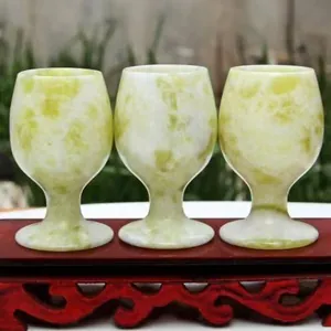 Handgesneden natuurlijke groene jade wijnbekers op een traditionele houten standaard