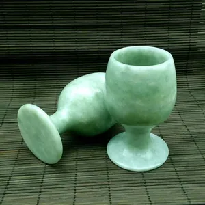 Detail van twee wijnglazen van natuurlijke groene jade steen op een bamboe matrasje