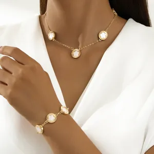 Dettaglio ravvicinato di un set di collana e bracciale floreali in oro su una modella.