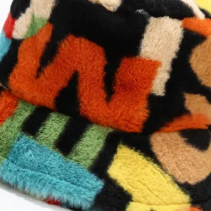 Macro detail showing the colorful abstract print and soft faux fur texture of the bucket hat.