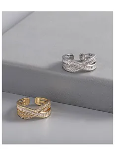 Close-up of gold and silver criss-cross rings featuring sparkling zircon stones pavé.
