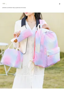 Detalle del set de 3 mochilas escolares rosa tie-dye sostenido por una modelo al aire libre