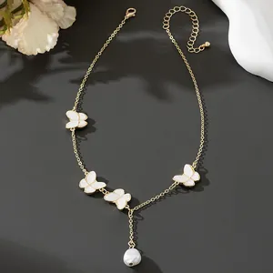 Elegante collana dorata con motivi a farfalla bianchi e un ciondolo a goccia di perla