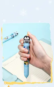 Détail d'un joli stylo à bille 10 couleurs pingouin de dessin animé tenu sur un cahier bleu