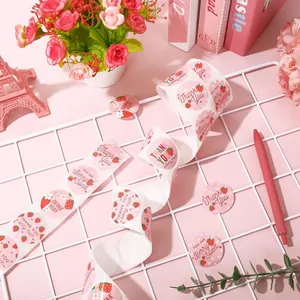 Detailed view of pink strawberry Thank You stickers on a white wire grid with props
