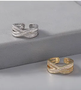 Detailed view of criss-cross rings with baguette and round zircons in gold and silver finish