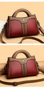 Detailansicht einer eleganten Handtasche in Rot und Braun mit Känguru-Logo aus Leder
