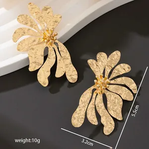 Dettaglio orecchini a fiore irregolare con texture martellata dorata e dimensioni.