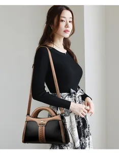 Nahaufnahme eines Modells mit einer eleganten schwarz-beigen Umhängetasche aus Leder