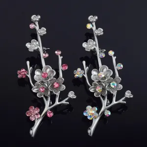 Detailed view of matte silver plum blossom brooches with colorful and pink rhinestones.