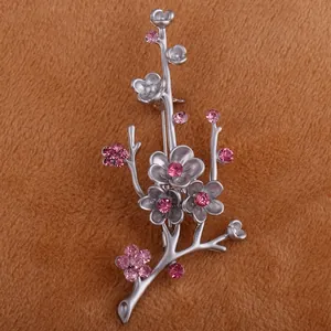 Detail shot of a matte silver plum blossom brooch with shimmering pink rhinestones