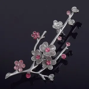 Detailed macro view of a vintage plum blossom brooch with pink crystals on matte silver
