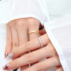 Close-up of minimalist knot rings with small zircons on a hand with white gauzy sleeve.