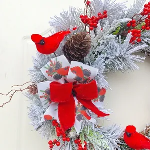 Ghirlanda natalizia innevata con uccello cardinale rosso e fiocco decorativo grande