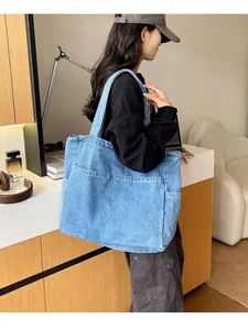 Lifestyle view showing a large capacity light blue denim tote bag worn over the shoulder.