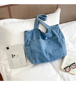 Detail view of large denim tote bag showing size comparison with tablet