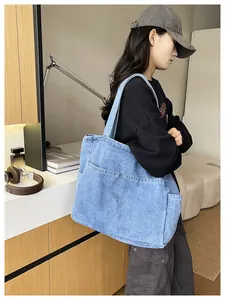 Detailed side view of a large denim tote bag worn by a model in a cozy indoor setting