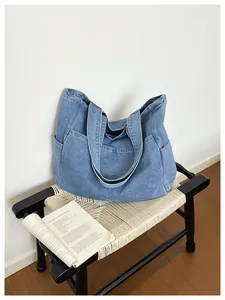 Large capacity blue denim tote bag with side pockets on a minimalist woven bench