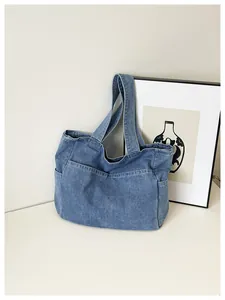 Close-up of a blue denim tote bag with multiple pockets in a minimalist setting