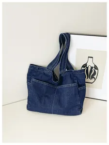 Detailed view of a minimalist dark blue denim tote bag with multiple functional pockets