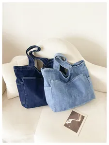 Lifestyle shot of dark and light blue denim tote bags on a minimalist white sofa