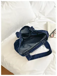 Detailed interior view of a minimalist blue denim tote bag on a white bed setting.