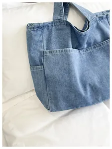 Close-up view of a minimalist blue denim tote bag with multiple exterior pockets