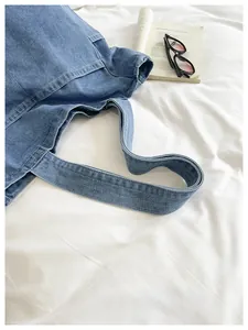 Close-up of blue denim tote bag showing wide shoulder strap and durable stitching