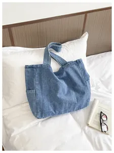 Large blue denim tote bag for women displayed on a cozy white bed lifestyle scene