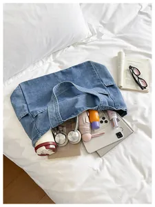 Detail view showing large capacity of blue denim tote bag with daily essentials inside.